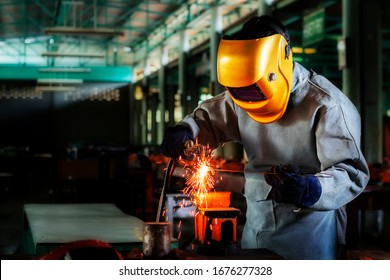 A craftman is welding with workpiece steel.Working person About welder steel Using electric welding machine There are lines of light coming out and safety equipment in factory industry.