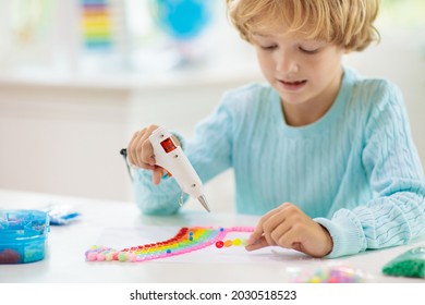 Crafts For Kids. Child With Hot Glue Gun. Creative Little Boy Sticking Buttons And Beads In Rainbow Design. Art And Creativity Class In School Or Kindergarten. Preschool Kid With Fun Diy Project.