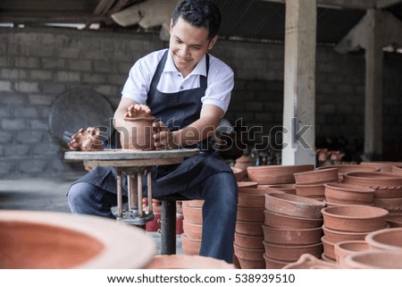 craftsman artist making pottery vase from fresh wet clay on pottery wheel