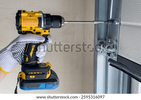 A craftsman assembles sectional doors using a screwdriver. The concept of sectional door installation.
