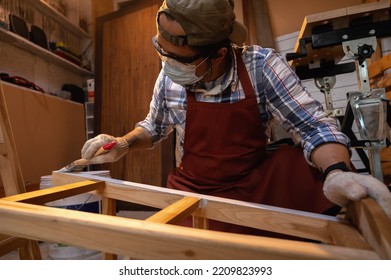 Craftsman, Carpenter Using A Paintbrush Painting To Wooden Bar Chair Handmade At Woodworking Workshop Or Carpentry Workplace.