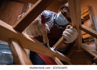 Craftsman, Carpenter Using A Paintbrush Painting To Wooden Bar Chair Handmade At Woodworking Workshop Or Carpentry Workplace. Selective Soft Focus On The Paintbrush.