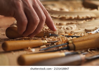 Craftsman carving with a gouge. Woodwork. Workbench with equipment. Wood carving tools. Chisels for carving