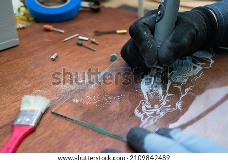 A craftsman does glass engraving with a rotary tool