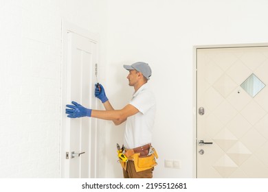 A Craftsman With An Electric Screwdriver In His Hands Inserts A Lock Into The Door. Tighten The Screw In The Door Lock