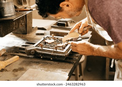 A craftsman focuses intently while adding colors into a hydraulic tile mold in an artisan workshop. He uses specialized tools for precision and accuracy in creating a decorative tile design. - Powered by Shutterstock