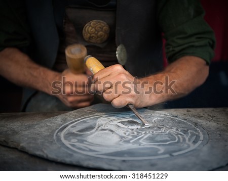 Craftsman hands working with a chisel on board