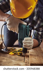 Craftsman In Helmet And Gloves Holding Drill At Work. Male Contractor Woodworking With Building Tools. 