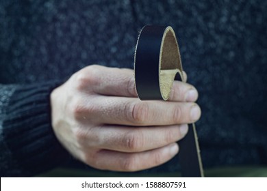 Craftsman holds a Genuine Black Leather Strap In His Hand. Handmade Concept. Small Business