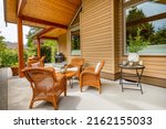 Craftsman home cedar siding solid wood pillars patio veranda deck grassy green yard blue sky and landscaping