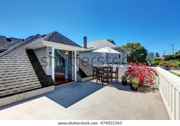Craftsman house roof top terrace with living area\
with plant pots. Table set with umbrella. View of attic bedroom.\
Northwest, USA