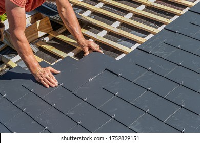 Craftsman is installing a slate roof. Professional roof workers installing roof for a old house .Working on rooftop. 