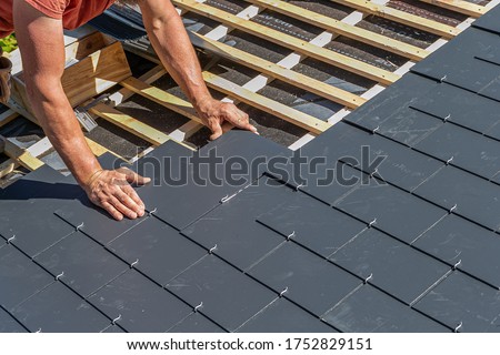 Craftsman is installing a slate roof. Professional roof workers installing roof for a old house .Working on rooftop. 