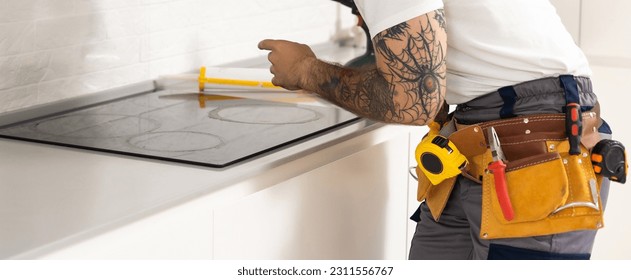 craftsman installs hob in kitchen. Household Appliance Installation Services Concept - Shutterstock ID 2311556767