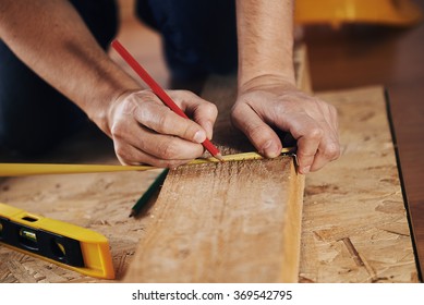 Craftsman measuring wooden plank with ruler on the floor. Concept of diy, woodworking and home renovation.  - Powered by Shutterstock