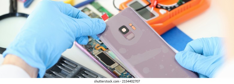 Craftsman In Rubber Gloves Closing Cover Of Mobile Phone In Workshop Closeup