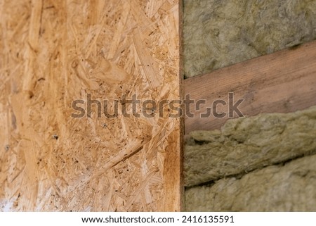 Craftsman skillfully screws OSB Plate to Wooden Frame on one side, complements the other with Mineral Wool.