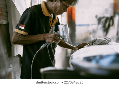 Craftsman surfboard working in a repair workshop, man spray painting a surfboard. - Powered by Shutterstock