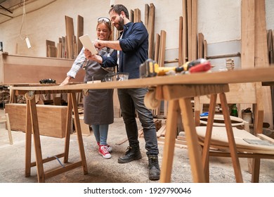 Craftsman trainer and wife as carpenter apprentice with tablet PC in the workshop