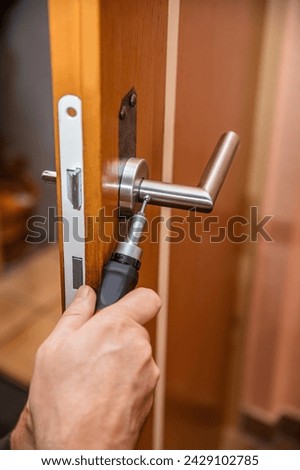 craftsman uninstalling a panel or door mounting, maybe key escutcheon from the keyhole of a door, concept door lock diy