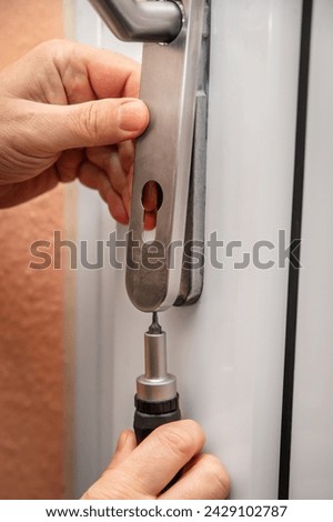 craftsman uninstalling a panel or door mounting, maybe key escutcheon from the keyhole of a door, concept door lock diy