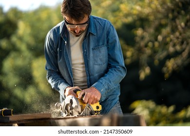 Craftsman working with circular saw at construction site