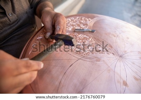 craftsman working with decoration pattern on metal plate
