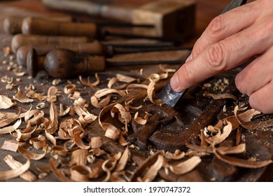 CRAFTSMAN'S HAND CARVING WOOD WITH FIRMER GOUGE CHISEL AND WOODEN HAMMER MALLET IN THE WORKSHOP. HANDICRAFTS AND DIY CONCEPT.