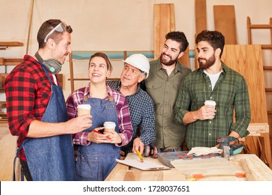 Equipo de artesanos y aprendices tomando un descanso para el café en el taller de carpintería
