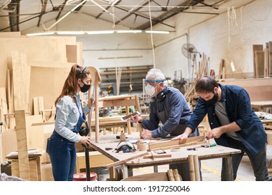 Craftsmen team with face masks because of Covid-19 in the carpentry workshop - Powered by Shutterstock