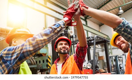 Craftsmen team is successful and makes high five motivation in a factory hall