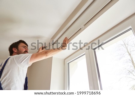 Craftsmen as window fitters assemble a blind on the window of an apartment