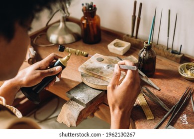 Craftsperson making jewelry design using flame torch and tool in the workshop. Jeweler working at work desk with traditional tools in her studio. - Powered by Shutterstock