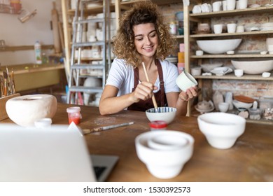 Craftsperson painting a bowl made of clay in art studio - Powered by Shutterstock