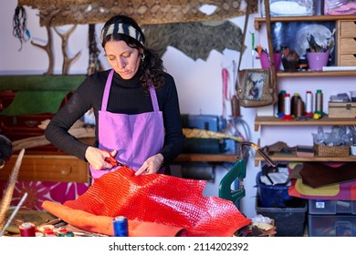 Craftswoman cutting leather at the work table in her studio - Powered by Shutterstock