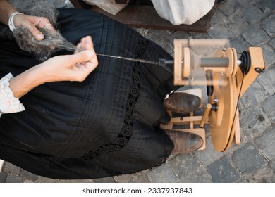 Craftswoman using an spinning wheel to turn wool into yarn - Powered by Shutterstock