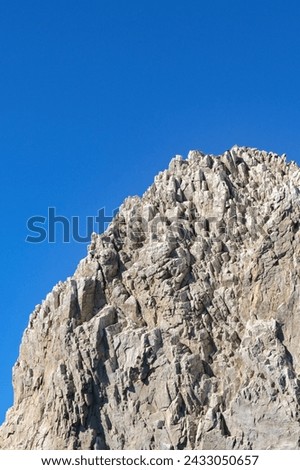 Craggy rock on a coastline against a deep blue sky. No people.