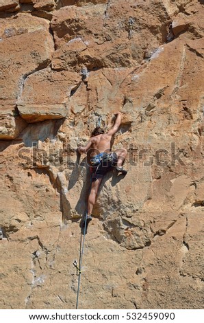 The cragsman is climbing on the vertical wall in the Prades mountains. Siurana is a world-class mountaineering destination. There are steep walls, slabs, overhangs and other limestone landforms.