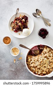 Cramble with berries, apples, almond and ball of vanilla ice cream on gray stone background. Flat lay