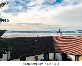 Cramond, Scotland / United Kingdom - July 11 2018: A photograph of a seaside cottage in the village of Cramond with a view of the Firth of Forth river at low tide in the early evening. 