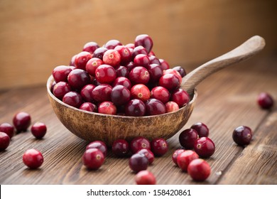 Cranberries in wooden bowl on wooden background. - Shutterstock ID 158420861