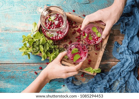 Cranberry beverage with mint, ice and berries in a box over vintage wooden background, top view