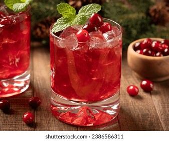 Cranberry cocktail with fresh cranberries and mint leaves on wooden surface. Fir tree branch and pine cones in background - Powered by Shutterstock