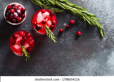 Cranberry Drink Cocktail With Ice And Rosemary On Dark Background, Copy Space, Top View