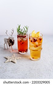 Cranberry And Rosemary Gin Tonic And Lemon Fizz. Colorful Christmas Cocktails In Glasses On White Table.  Fresh Holiday Drinks.