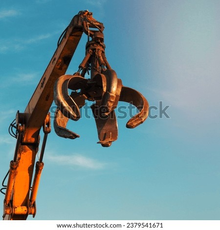 crane arm with open claw on clear blue sky