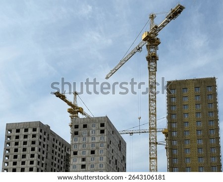 Crane and building construction construction site. Multi Storey Residential Buildings construction. Construction crane on Housing. Building site with cranes against sky. Tower crane on formworks.