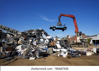 Crane with claw tossing trucks at scrapyard recycling center - Powered by Shutterstock