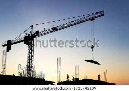 Crane construction Lifting Steel Material to high Building site and workers working Silhouette on site with sunlight sunset sky in the Evening, Tower Crane 