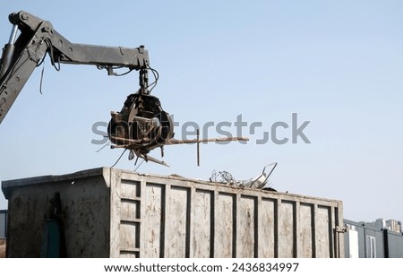 Crane grabber loading a truck with metal scrap. Metal waste on the junkyard. 